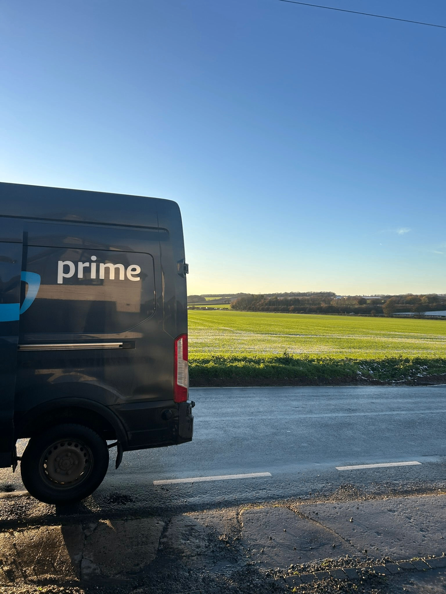 Amazon Prime delivery van parked on a country road at sunrise